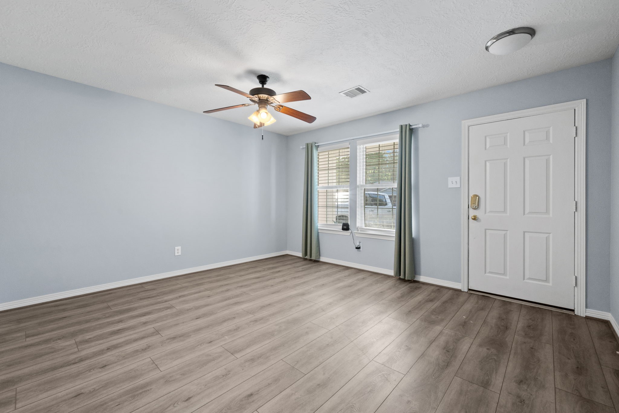 21893 Pinewilde Court Porter, TX 77365 - Photo 10 of 25 an empty room with wooden floor fan and windows