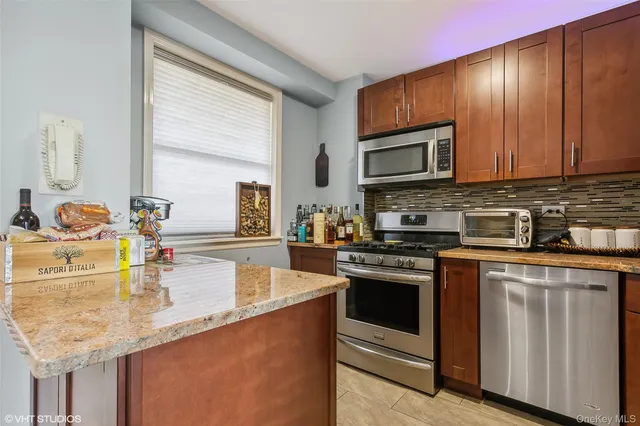 a kitchen with stainless steel appliances granite countertop a stove a sink and a microwave