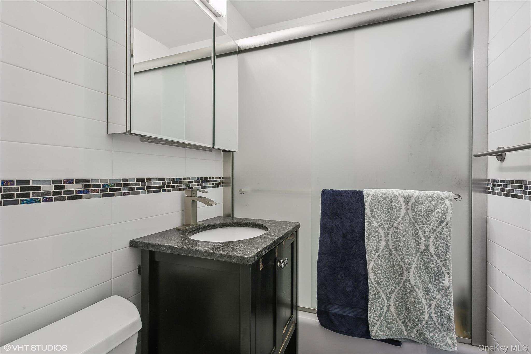 5800 Arlington Avenue, Unit 19L Bronx, NY 10471 - Photo 8 of 19 a bathroom with a granite countertop sink and a mirror