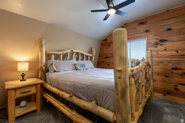 1505 West Elk Ridge Drive Alton, UT 84710 - Photo 19 of 53 Bedroom with vaulted ceiling, wooden walls, a textured ceiling, dark colored carpet, and a ceiling fan