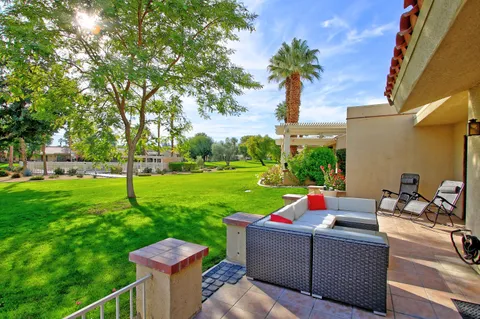 a view of a patio with couches dining table and chairs with wooden fence and trees