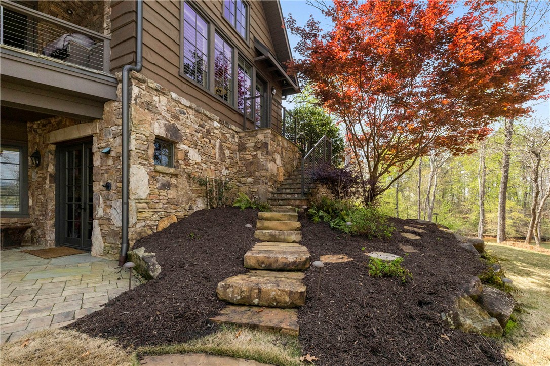 195 Village View Drive Sunset, SC 29685 - Photo 7 of 48 This captivating exterior showcases a multi-level home with rich wood and natural stone accents, complemented by lush landscaping.