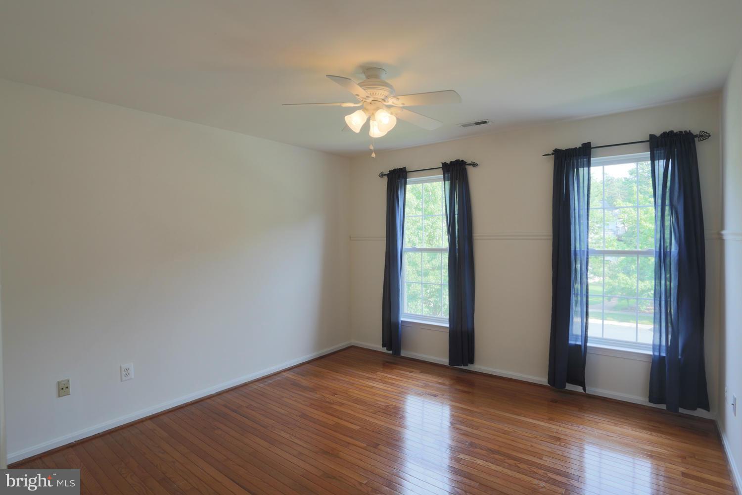 1518 Ringe Drive Severn, MD 21144 - Photo 11 of 30 an empty room with wooden floor chandelier fan and windows