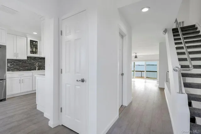 a kitchen with stainless steel appliances granite countertop a refrigerator a oven a sink dishwasher and white cabinets with wooden floor