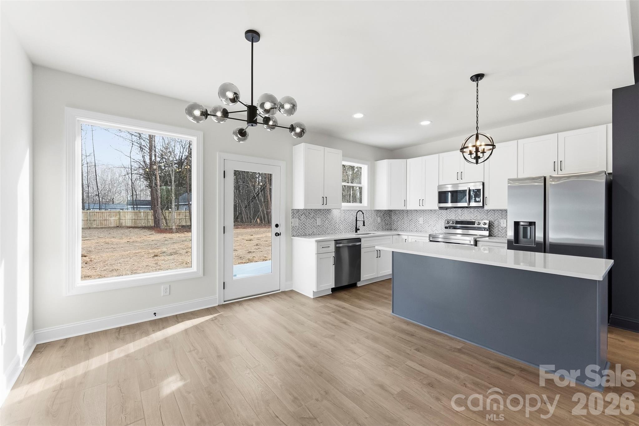1734 Barnhardt Road China Grove, NC 28023 - Photo 11 of 45 a large kitchen with stainless steel appliances granite countertop a stove a sink dishwasher a refrigerator and white cabinets with wooden floor