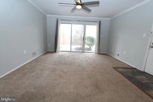 an empty room with a ceiling fan and window