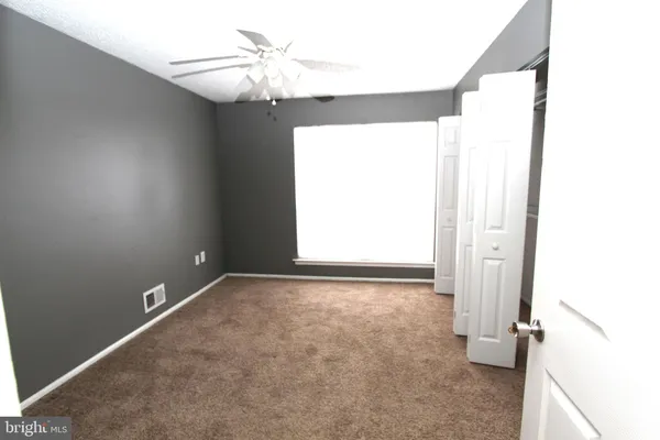 an empty room with a window and a ceiling fan