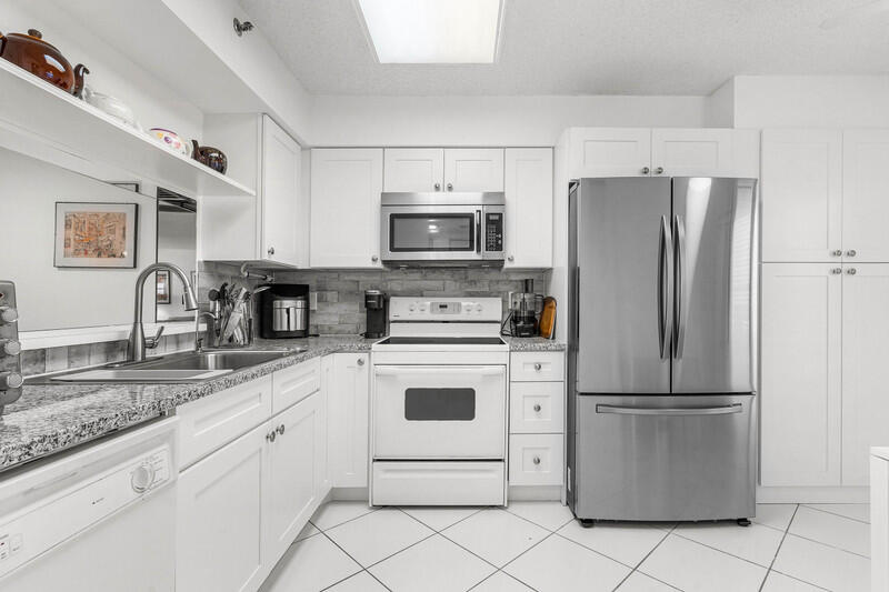 7310 Ashford Place, Unit 803 Delray Beach, FL 33446 - Photo 12 of 26 a kitchen with cabinets a refrigerator and a sink