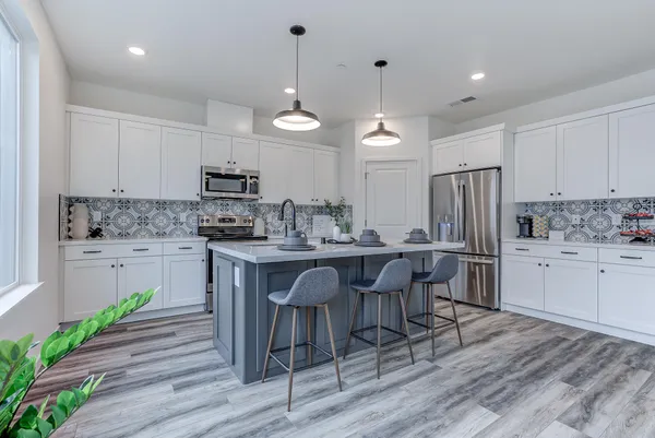 a kitchen with kitchen island granite countertop a sink a center island and stainless steel appliances