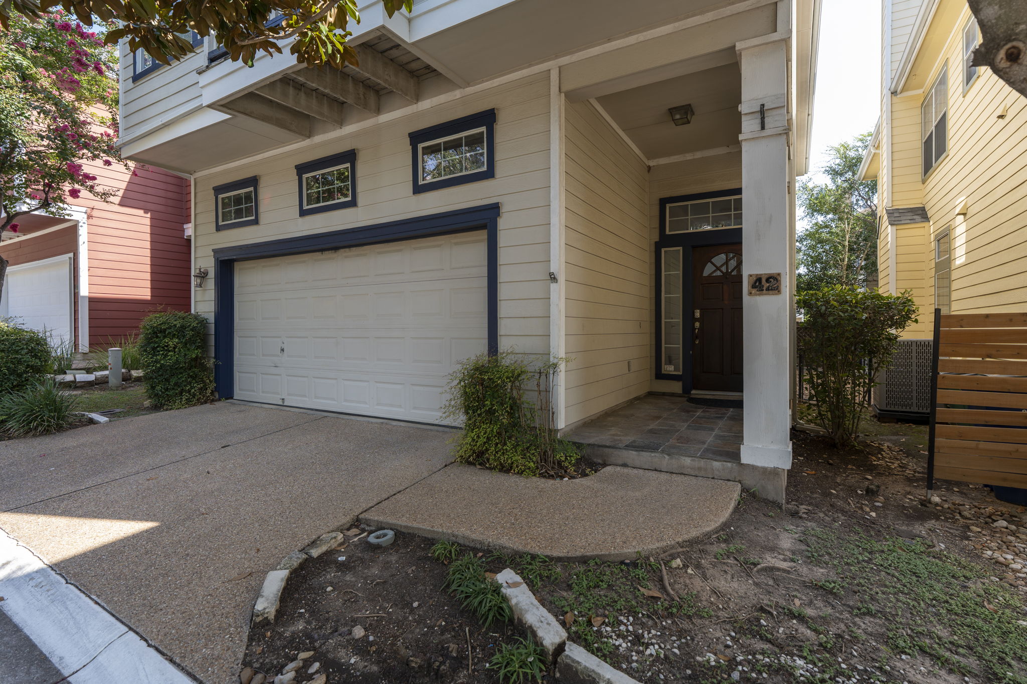 6704 Menchaca Road, Unit 42 Austin, TX 78745 - Photo 2 of 21 A welcoming entry features a paneled garage door and a front door with decorative glass, complemented by a simple, well-maintained landscape.