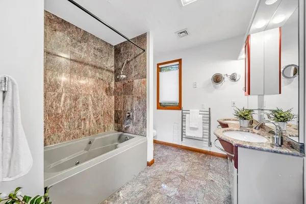 a bathroom with a granite countertop sink a mirror a bathtub and shower
