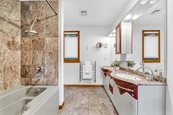 a bathroom with a granite countertop tub sink and mirror