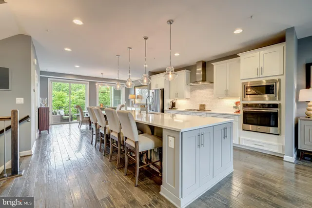 a kitchen with stainless steel appliances kitchen island granite countertop a table chairs sink and cabinets