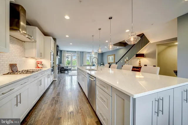 a large kitchen with stainless steel appliances kitchen island a large counter top a sink a stove and a wooden floors