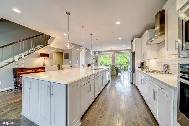 a large kitchen with stainless steel appliances kitchen island wooden floors and white cabinets