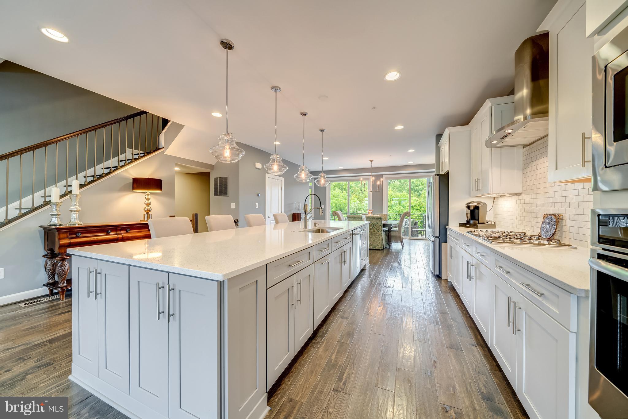 1521 Ribbon Limestone Terrace Southeast Leesburg, VA 20175 - Photo 17 of 34 a large kitchen with stainless steel appliances kitchen island wooden floors and white cabinets