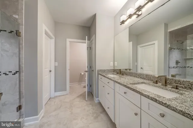 a spacious bathroom with a granite countertop sink a mirror and a shower