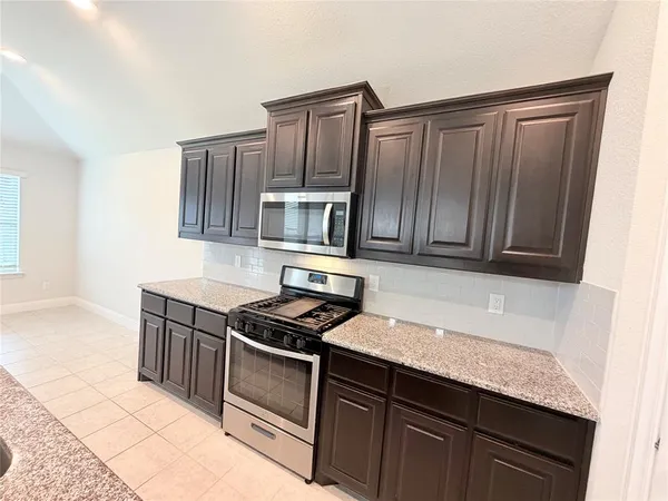 a view of kitchen with refrigerator stove microwave and cabinets