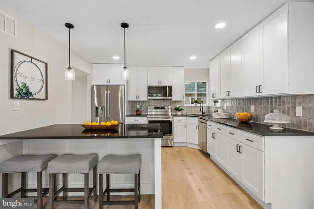 a kitchen with stainless steel appliances granite countertop a sink a stove a refrigerator cabinets and chairs