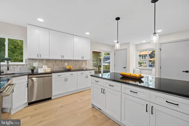 a kitchen with white cabinets and window