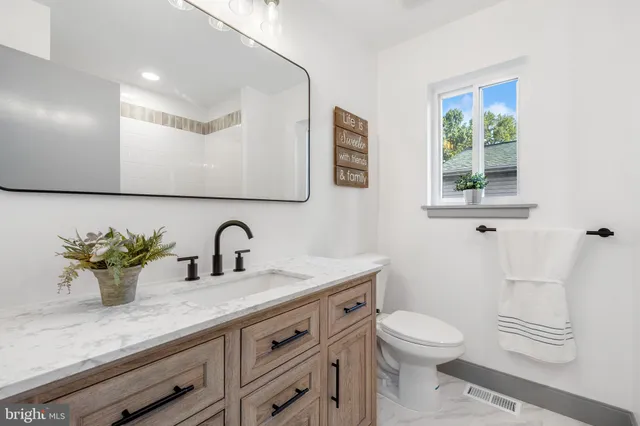 a bathroom with a granite countertop sink a toilet and mirror