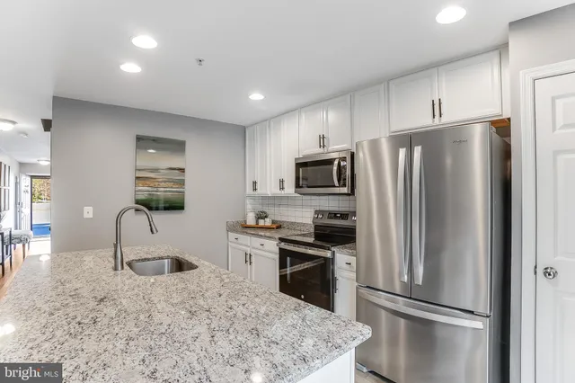 a kitchen with stainless steel appliances granite countertop a refrigerator a stove a sink a microwave and a refrigerator