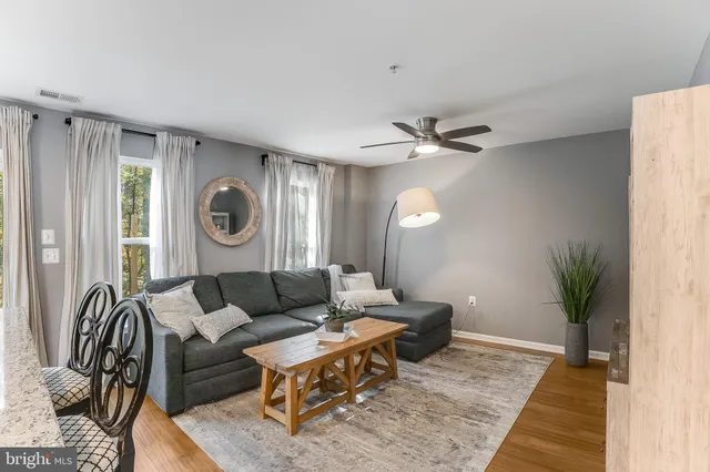 a living room with furniture a clock on wall and a table