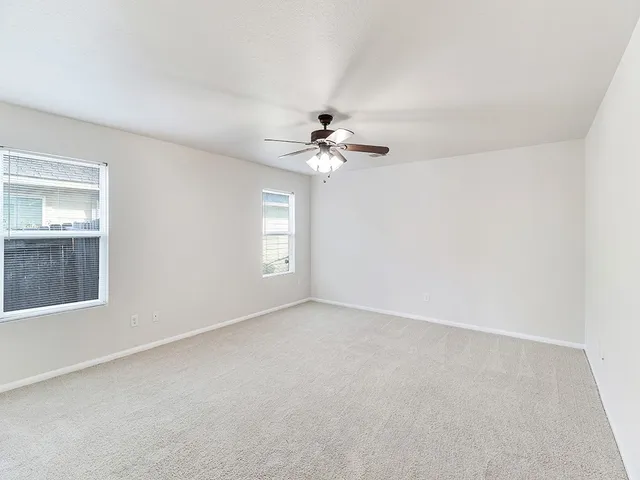 an empty room with windows and chandelier fan
