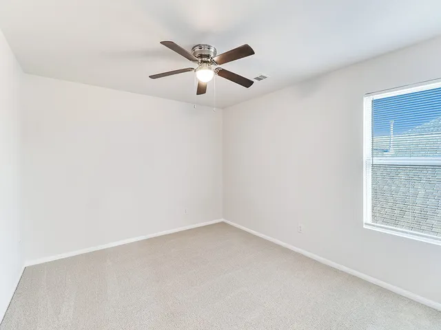 an empty room with a window and a fan