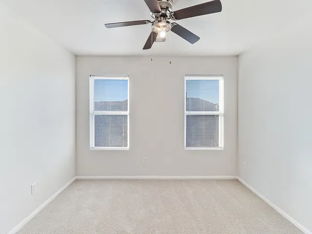 an empty room with a window and ceiling fan