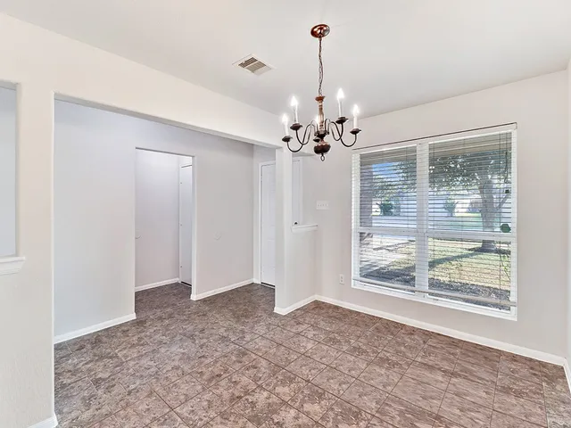 a view of a livingroom with a chandelier a kitchen in the background