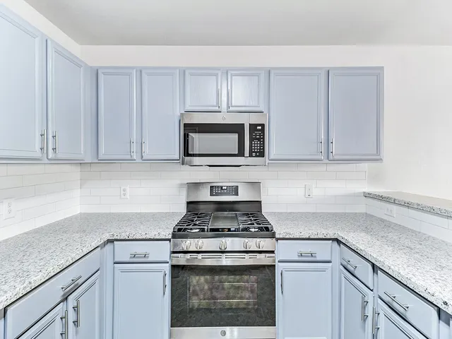 a kitchen with granite countertop white cabinets and stainless steel appliances
