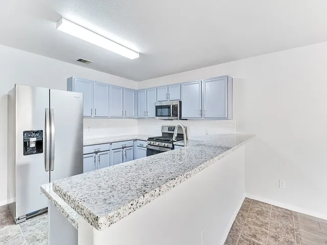 a kitchen with granite countertop a refrigerator and a sink
