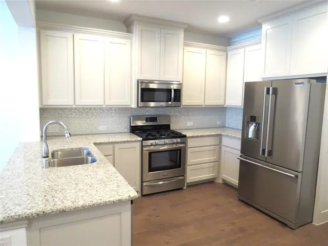 a kitchen with refrigerator a microwave a sink and cabinets