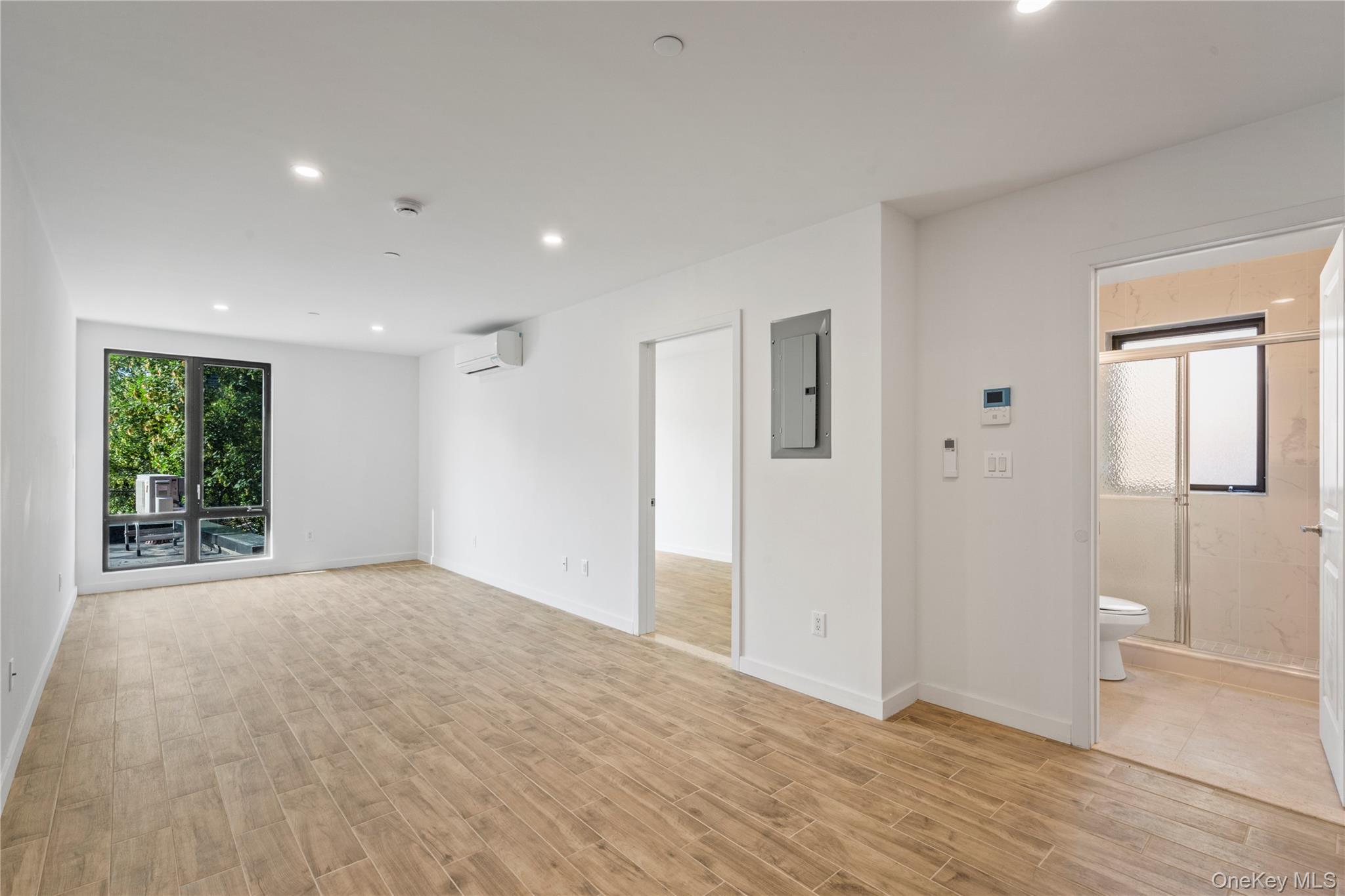 213-41 38th Avenue, Unit 2B Queens, NY 11361 - Photo 2 of 12 a view of an empty room with wooden floor and a window
