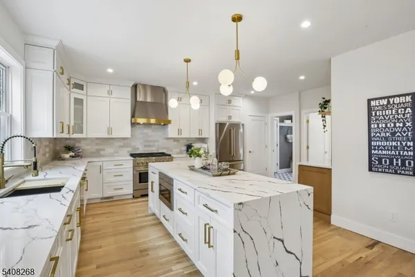 a kitchen with stainless steel appliances kitchen island a sink stove cabinets and wooden floor