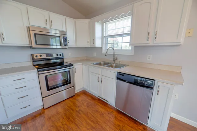 a kitchen with white cabinets stainless steel appliances and sink