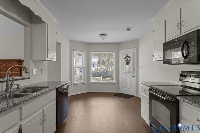 a kitchen with granite countertop a stove a sink and a refrigerator