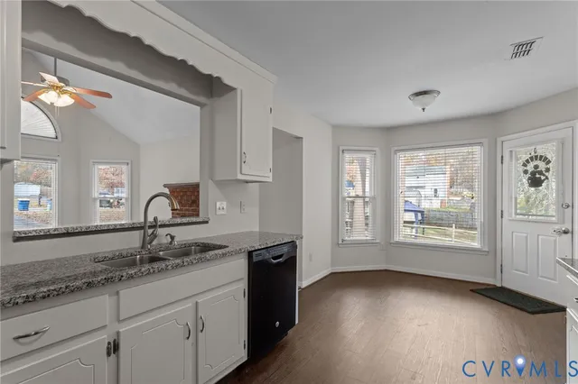 a kitchen with granite countertop white cabinets and a wooden floor