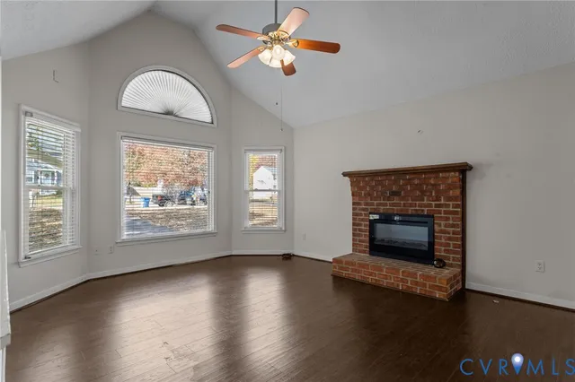 an empty room with wooden floor fireplace and windows