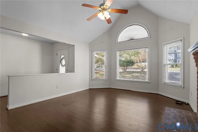 an empty room with wooden floor chandelier fan and windows