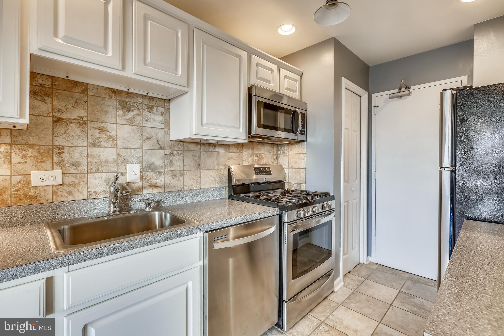 a kitchen with stainless steel appliances white cabinets a stove top oven a sink and dishwasher