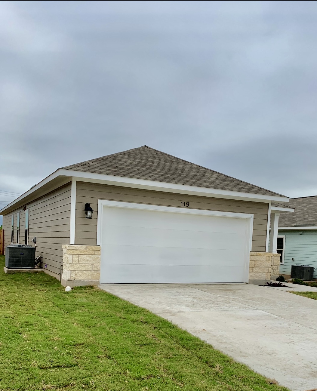 119 Wild Wind Cove Jarrell, TX 76537 - Photo 2 of 16 View of property exterior featuring cooling unit, stone siding, and a garage