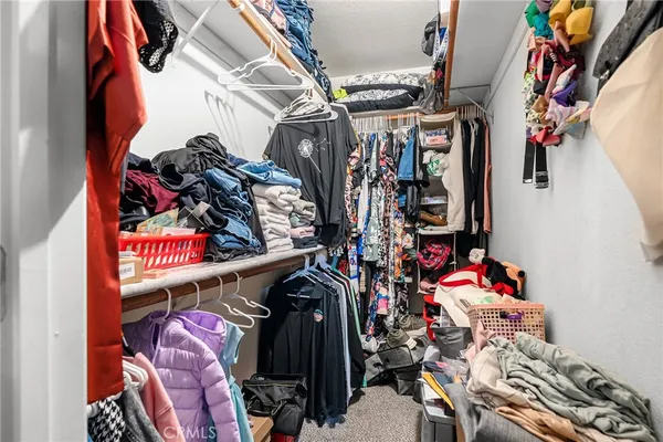 a view of walk in closet with clothes and shoes