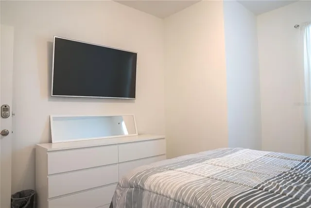 a bedroom with a flat screen tv and a window