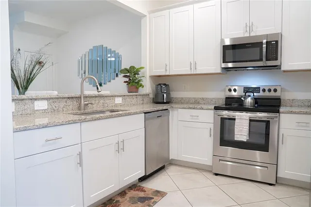 a kitchen with granite countertop white cabinets and stainless steel appliances