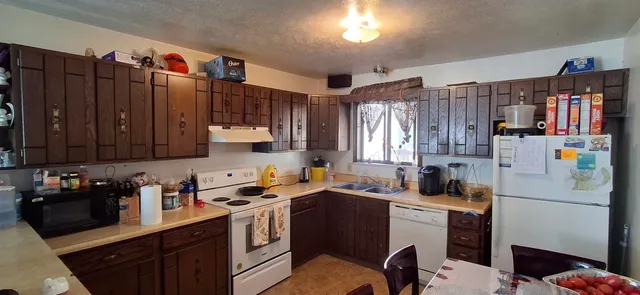 a room with a refrigerator a stove a sink dishwasher and wooden cabinets with wooden floor