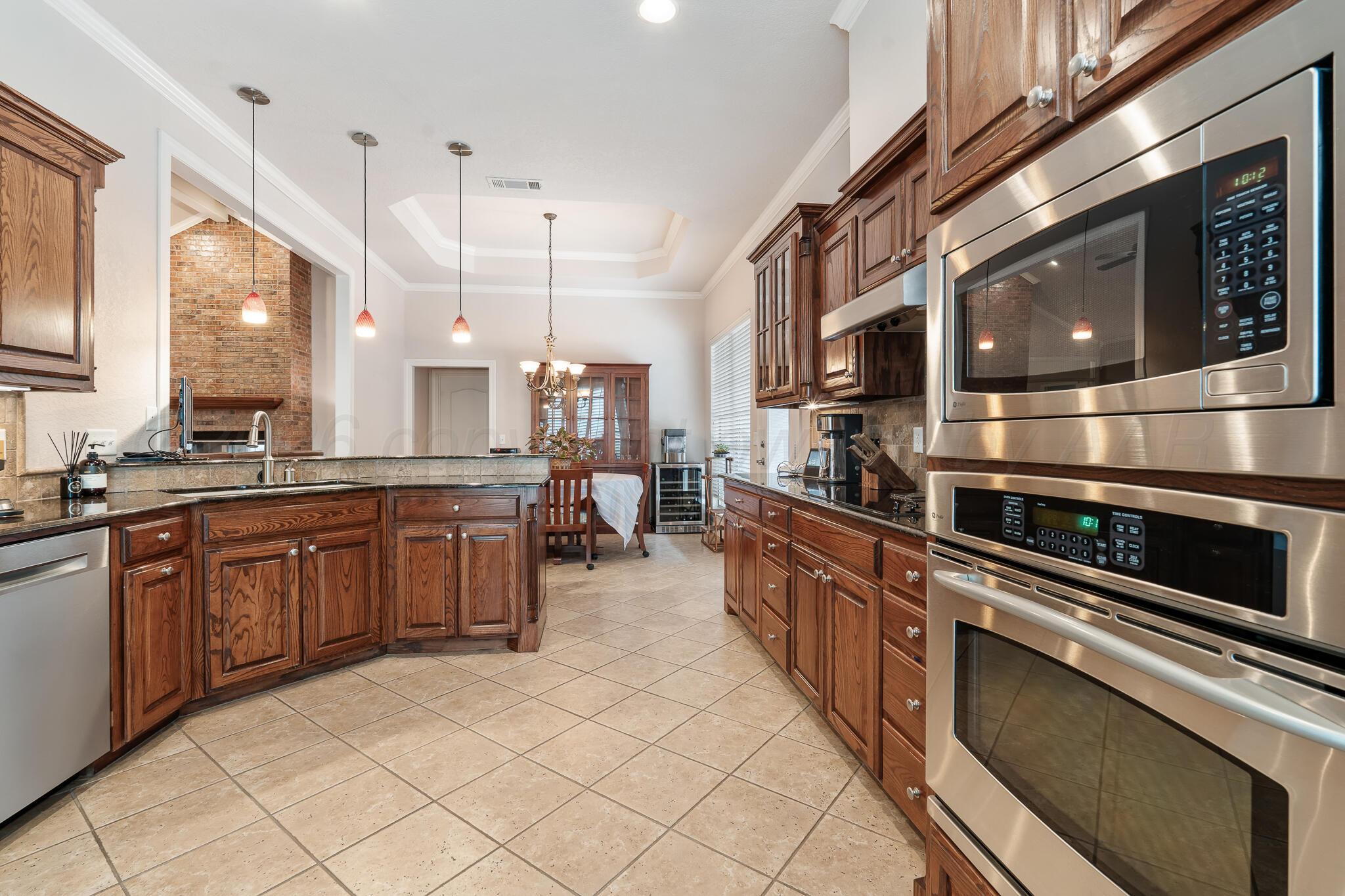5008 Wesley Road Amarillo, TX 79119 - Photo 9 of 47 a kitchen with stainless steel appliances kitchen island granite countertop a stove a sink and a microwave