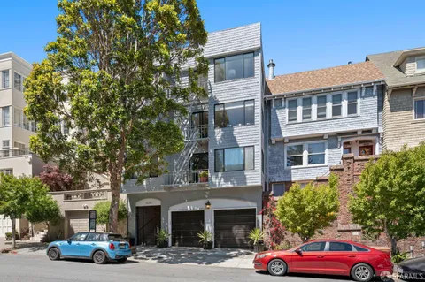 a front view of a building with cars parked