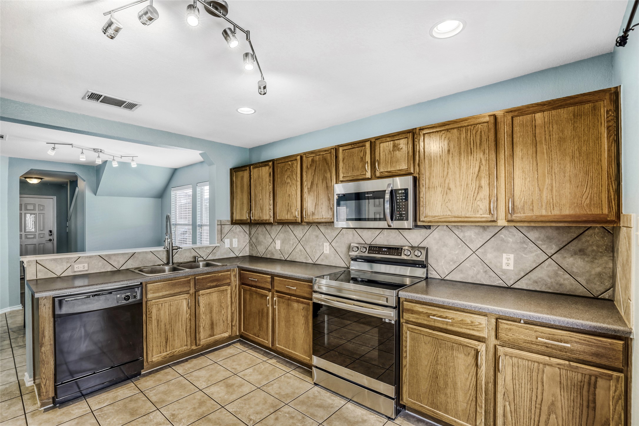 5624 Colinton Avenue Austin, TX 78754 - Photo 15 of 38 Kitchen with stainless steel appliances, wood finish cabinetry, nice countertops, light tile patterned flooring, and track lighting